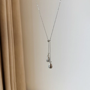 Close-up of a silver Y-chain necklace featuring two sleek teardrop pendants in a polished finish
