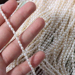 Hand holding high-luster 4mm natural freshwater seed pearls for DIY jewelry making