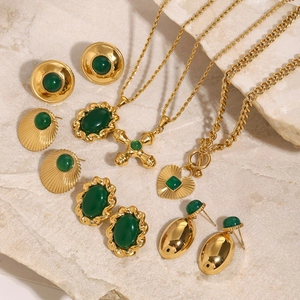 Vintage gold jewelry set with emerald green stones on a marble background