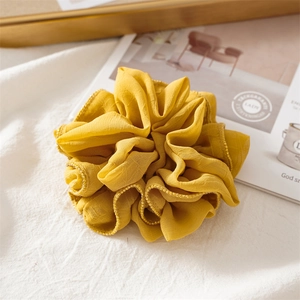 Detail of yellow chiffon scrunchie with delicate gold beaded edge on linen background
