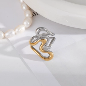 Détail d'une bague bicolore aux formes ondulées avec finitions dorées et argentées