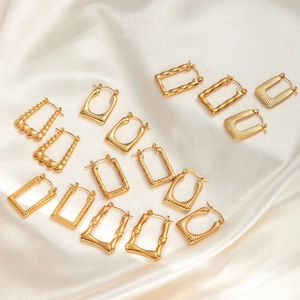 Schicke goldfarbene geometrische Creolen im Set mit verschiedenen Texturen auf weißer Seide