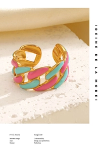 Detail of gold chain ring with pink and blue enamel inlay on a stone pedestal