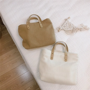 Top view of two woven tote bags in khaki and beige with smooth brown leather handles