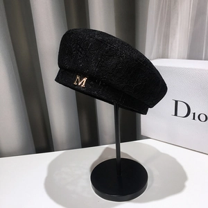 Elegant black lace beret for women with gold M logo on a minimalist hat stand