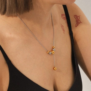 Detail of a two-tone beaded Y-necklace in 18K gold and silver on a female model
