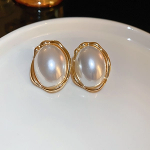 Vue macro de boucles d'oreilles perles vintage avec bordure dorée irrégulière chic