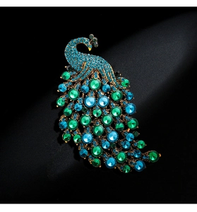 Detailed close-up of peacock brooch with blue and green crystals on a gold base