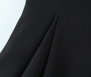 Close-up of the black fabric texture and stitching detail on the contrast mini dress
