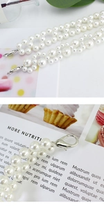 Detailed macro view of white pearls belt accessory with silver metal lobster clasp