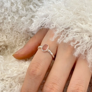 925 sterling silver ring with oval orange-pink crystal on white plush fabric