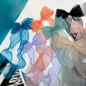 Flat lay detail showing multi-color sheer organza bow hair clips with long tassels