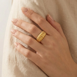 Close-up of golden croissant dome ring with a polished ribbed texture for unisex style