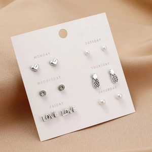 Detail of 6 pairs of pearl and zircon stud earrings on pink weekly card with silk background