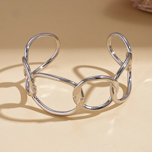 Macro detail of silver geometric intertwined cuff bracelet with polished finish