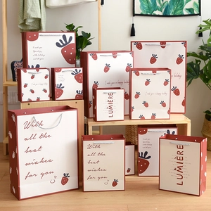 Creative strawberry-themed gift bags in various sizes with festive holiday greetings
