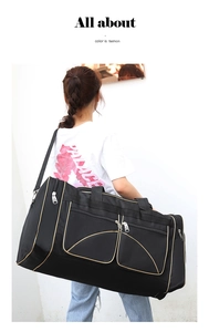 Rear view of model carrying the large black travel bag with gold piping detail