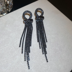Close-up of black zircon tassel earrings featuring geometric round studs and dangling rhinestones