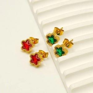 Gold star earrings with red and green zircon stones displayed on white steps