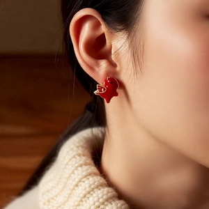 Close-up of red bird-shaped stud earring with gold wing detail on a model's ear