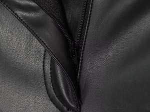 Close-up detail showing the black leather texture and smooth matching zipper on pants