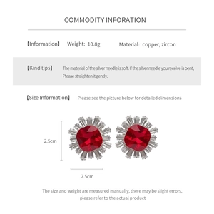 Detail view of flower-shaped copper earrings with red square zircon and silver needles