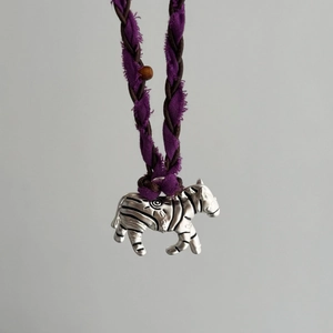 Gros plan du pendentif zèbre en métal avec cordon tressé violet et marron foncé