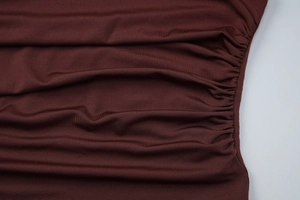 Detailed macro view of deep red ruched fabric texture on a slim-fit knit top
