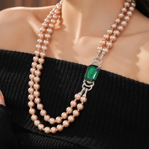 Dettaglio di collana vintage a due fili di perle con ciondolo quadrato di smeraldo