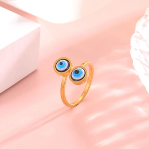 Adjustable golden evil eye ring with blue enamel eyes on a soft pink artistic background
