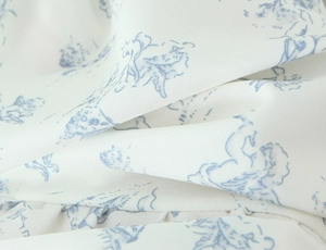 Vue macro détaillée de l'imprimé ange bleu clair sur le tissu floral lisse blanc cassé