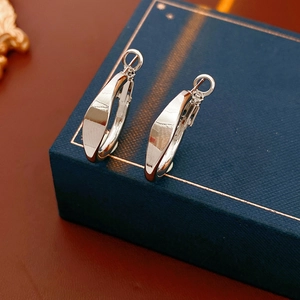 Detailed view of silver twisted hoop earrings with a high-gloss finish on a blue jewelry box