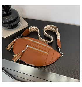 Close-up of brown litchi leather waist bag with tassel zipper and geometric strap
