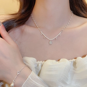 Detail of silver flower necklace with pearls and matching bracelet worn by a model