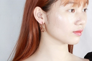 Detailed view of rose gold knotted double hoop earrings worn by a model