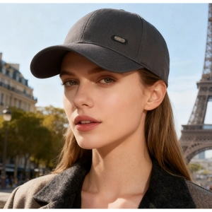 Detail of dark grey casual baseball cap with SPORT metal badge worn in an outdoor setting