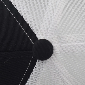 Detailed close-up of a trucker hat featuring breathable white mesh and black twill fabric