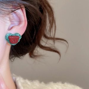 Macro shot of red bear heart earrings with green knitted border and silver needle studs