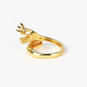 Detailed side view of gold-plated hand-shaped ring with a white cubic zirconia stone