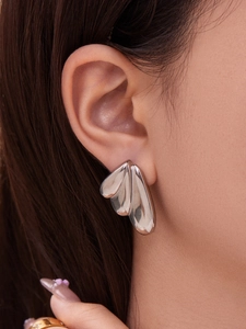 Close-up of polished silver fan earrings showing minimalist layered organic design