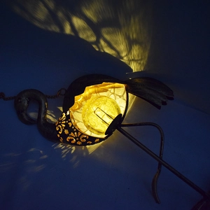 Solar flamingo light projecting warm decorative shadow patterns in a garden at night
