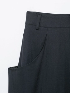 Detail of high-waist black trousers featuring belt loops and side pockets construction