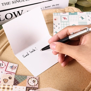 Minimalistische weiße Grußkarte aus Papier, handschriftlich auf einem Tisch verfasst