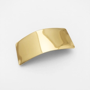 Close-up of curved golden metal hair clip with a smooth glossy finish on white background