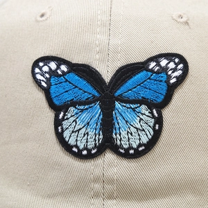 Casquette en coton beige avec broderie papillon complexe et textures 3D superposées