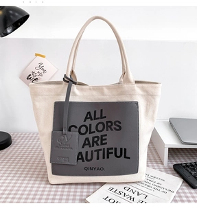 Detailed close-up of a canvas tote bag featuring an embossed grey leather patch and logo
