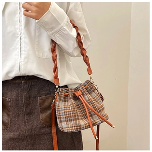 Plaid bucket bag shown as a crossbody with woven leather handle and drawstring closure