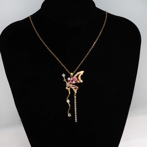 Détail du pendentif papillon doré avec pierres roses, perles et franges en strass