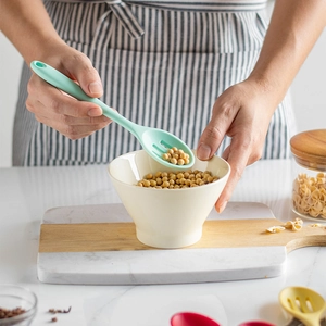 Mint green silicone slotted spoon lifting beans in a modern kitchen setting