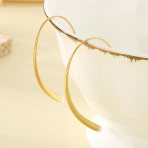Detailed view of minimalist gold curved hook earrings featuring delicate white pearls